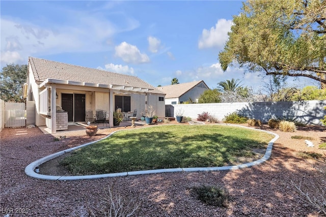 rear view of house featuring a fenced backyard, stucco siding, a yard, and a tile roof