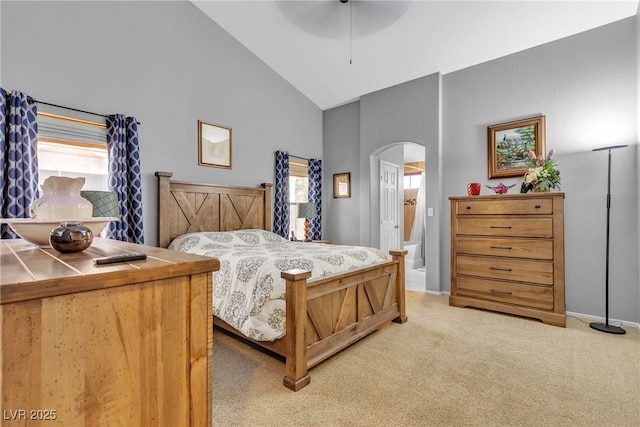 bedroom with high vaulted ceiling, multiple windows, light carpet, and arched walkways