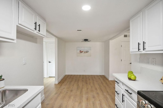4980 Indian River Dr Unit 447, Las Vegas, NV 89103 - kitchen with light wood finished floors, light countertops, white cabinetry, and electric range oven