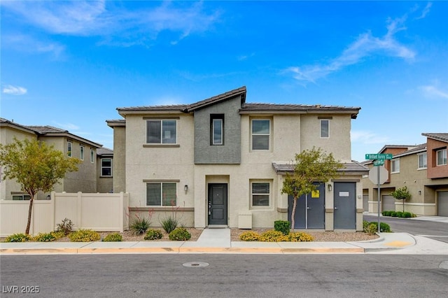 view of front facade featuring fence, stucco siding, and a tile roof