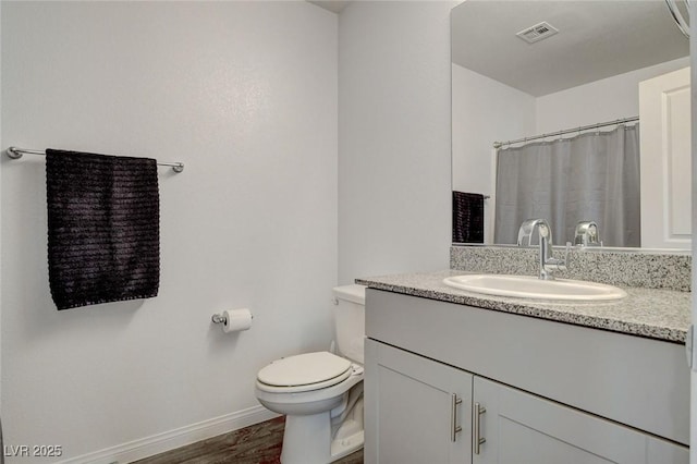 bathroom featuring visible vents, vanity, wood finished floors, toilet, and baseboards