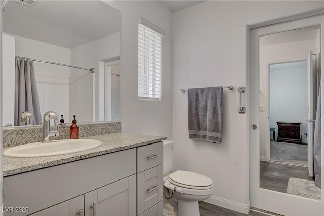 bathroom with vanity, toilet, baseboards, curtained shower, and wood finished floors