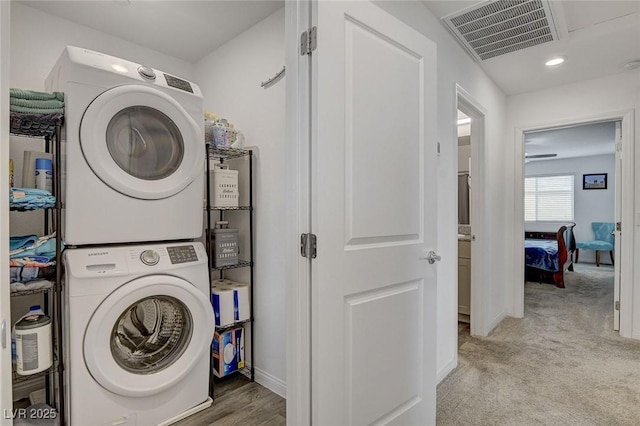 clothes washing area with stacked washer and dryer, laundry area, recessed lighting, baseboards, and visible vents