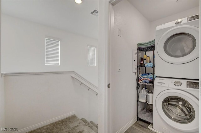 clothes washing area featuring baseboards, visible vents, and stacked washer and clothes dryer
