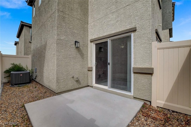 exterior space with fence, central AC unit, a patio area, and stucco siding