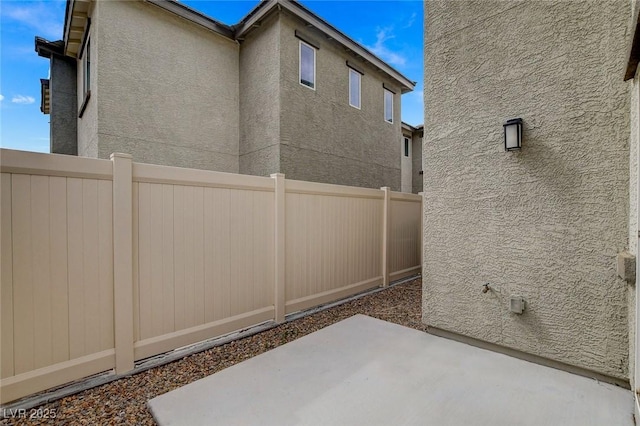 view of property exterior with a patio, fence, and stucco siding