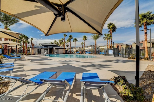 community pool with a patio, fence, and a residential view