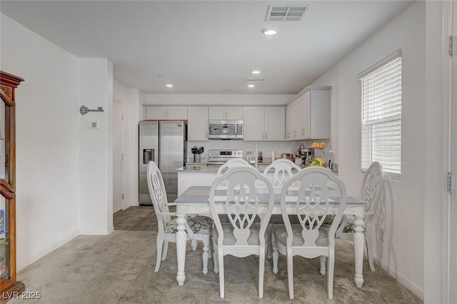 dining area featuring baseboards, visible vents, light carpet, and a wealth of natural light