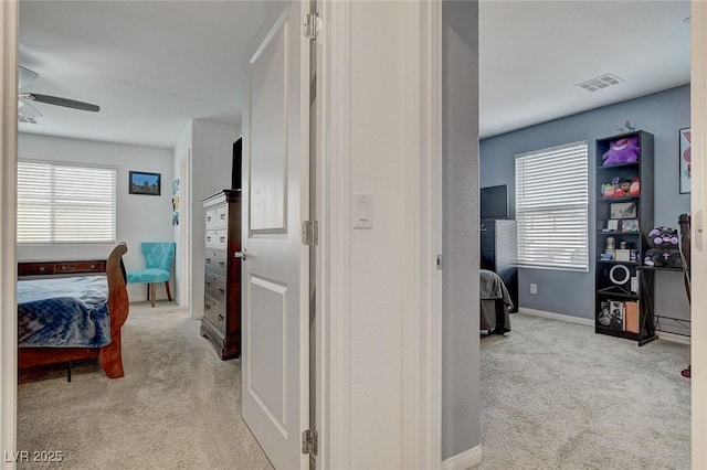 corridor featuring carpet flooring, visible vents, and a wealth of natural light