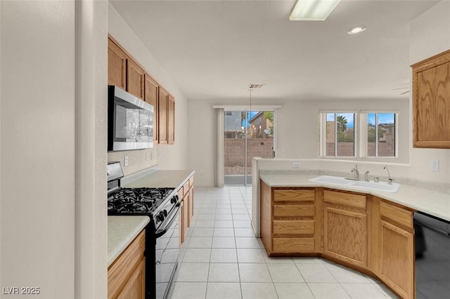 kitchen with black dishwasher, light countertops, stainless steel microwave, a sink, and gas stove
