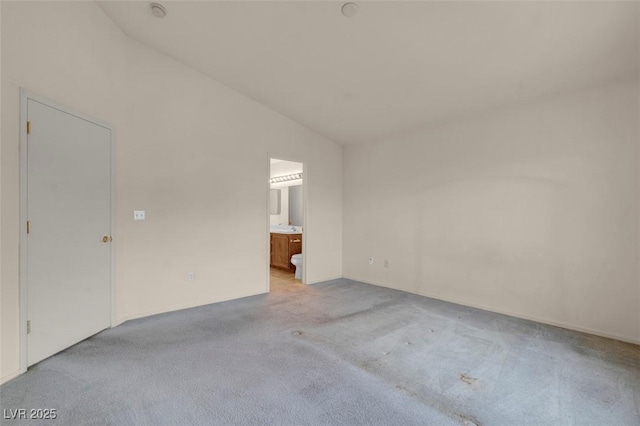 interior space with light colored carpet, ensuite bathroom, and lofted ceiling