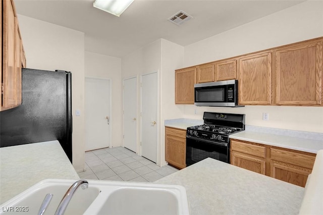 kitchen featuring visible vents, light countertops, a sink, and black appliances