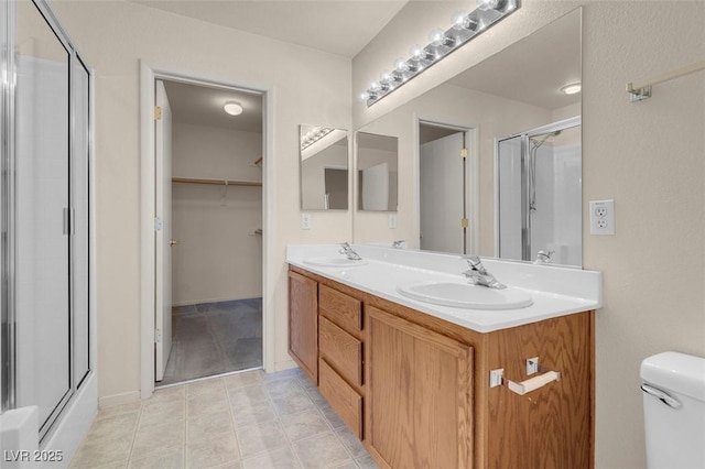 bathroom with double vanity, a sink, an enclosed shower, and toilet