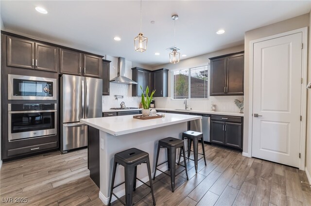 356 Silva Pl, Henderson, NV 89011 - kitchen with wall chimney range hood, a sink, stainless steel appliances, light wood-type flooring, and a kitchen bar