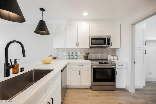 kitchen with a sink, appliances with stainless steel finishes, decorative backsplash, and white cabinetry