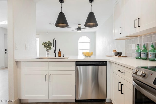 kitchen with a peninsula, ceiling fan, a sink, backsplash, and stainless steel appliances