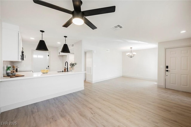 unfurnished living room featuring visible vents, light wood-style floors, baseboards, recessed lighting, and ceiling fan with notable chandelier