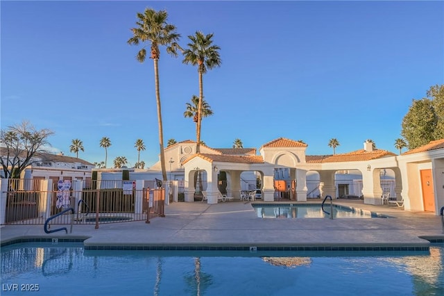 community pool with a patio area and fence