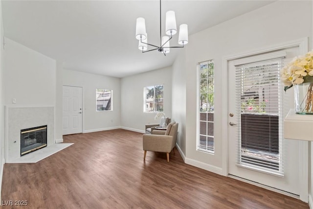 sitting room featuring wood finished floors, baseboards, a fireplace with flush hearth, and a notable chandelier