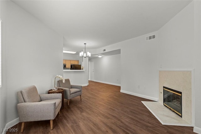 sitting room with a high end fireplace, visible vents, an inviting chandelier, dark wood-style flooring, and baseboards