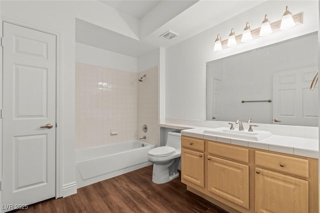 bathroom featuring toilet, wood finished floors,  shower combination, visible vents, and vanity