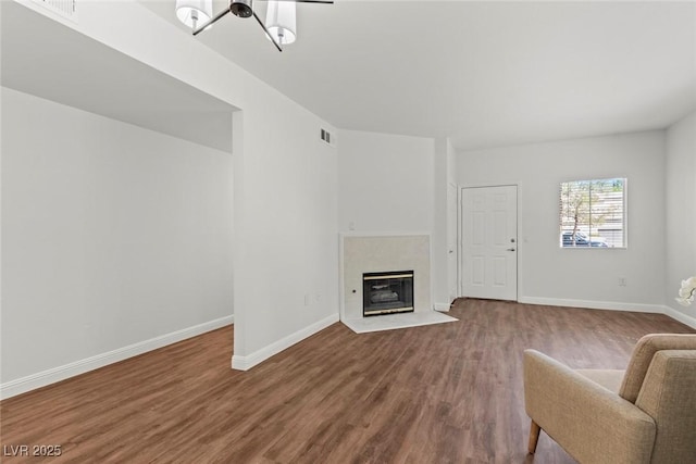living area featuring visible vents, wood finished floors, baseboards, and a fireplace with flush hearth