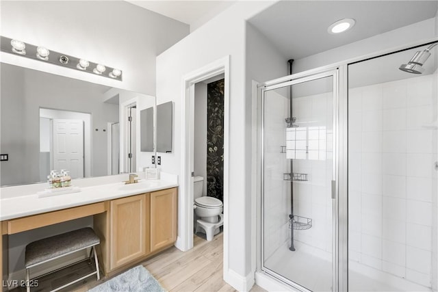 bathroom featuring toilet, a shower stall, wood finished floors, and vanity