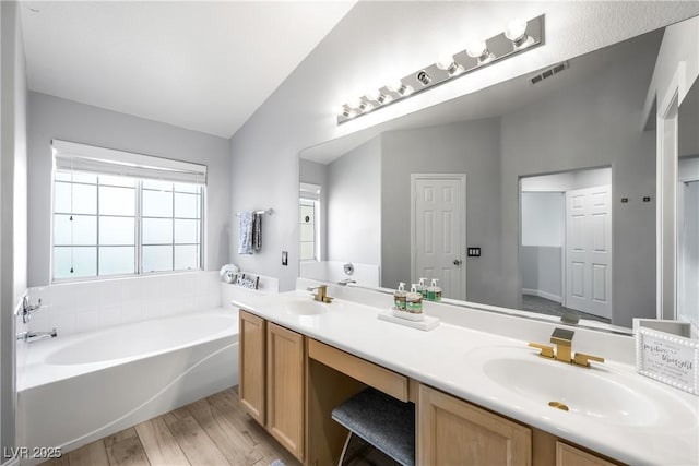 full bathroom with a sink, visible vents, a bath, and wood finished floors