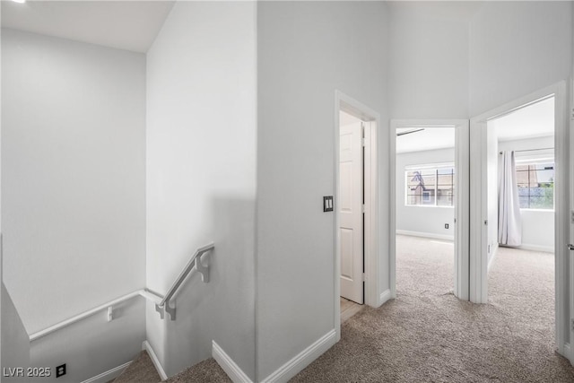 corridor featuring baseboards, carpet flooring, and an upstairs landing