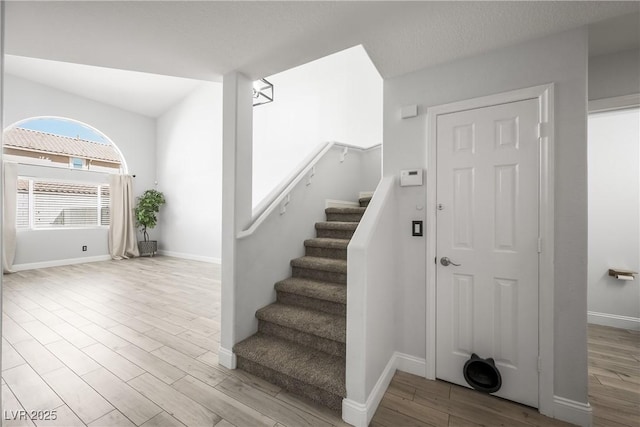 staircase with baseboards and wood finished floors