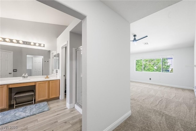bathroom with double vanity, baseboards, a stall shower, and lofted ceiling
