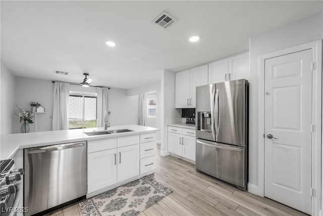 kitchen featuring visible vents, a sink, appliances with stainless steel finishes, and white cabinets