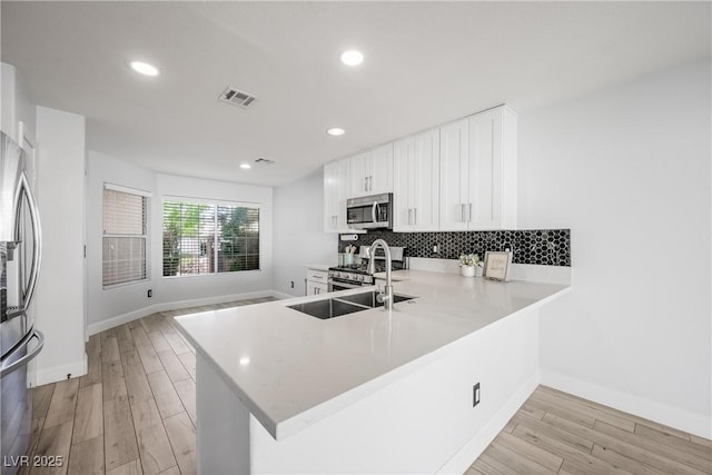 kitchen featuring decorative backsplash, visible vents, light countertops, baseboards, and stainless steel appliances