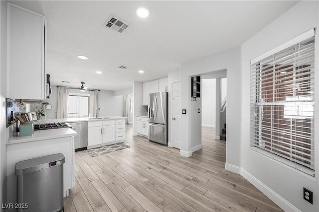 kitchen with visible vents, baseboards, white cabinetry, a sink, and appliances with stainless steel finishes