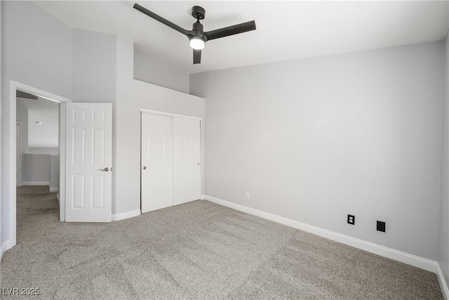 unfurnished bedroom featuring a closet, a ceiling fan, baseboards, a high ceiling, and carpet flooring