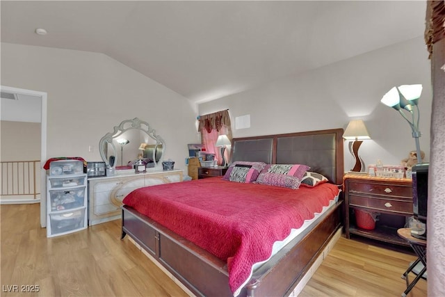 bedroom with vaulted ceiling, wood finished floors, and visible vents