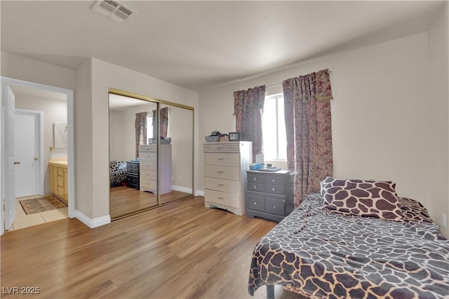 bedroom with light wood-style floors, multiple windows, a closet, and visible vents