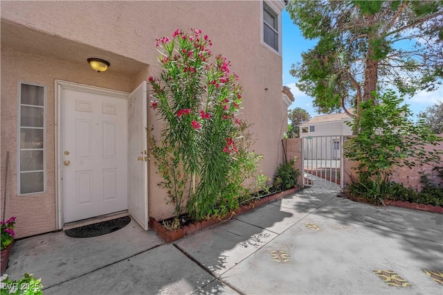 property entrance with a gate and stucco siding