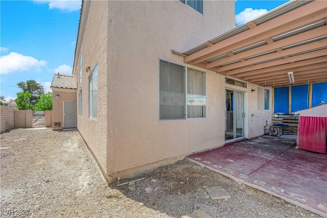 exterior space with a gate, a patio area, stucco siding, and fence