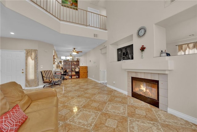 tiled living area with a fireplace, baseboards, visible vents, and a towering ceiling