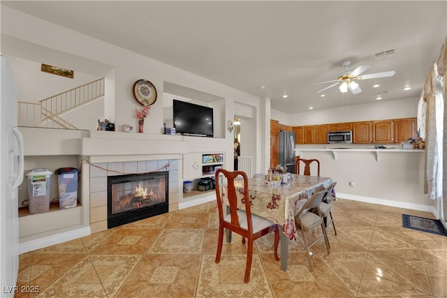 dining room featuring a ceiling fan, visible vents, a tile fireplace, recessed lighting, and light tile patterned flooring