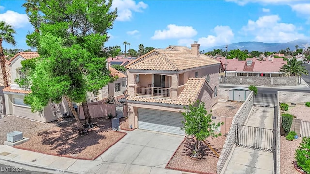 mediterranean / spanish-style house with a tile roof, stucco siding, a gate, concrete driveway, and a balcony