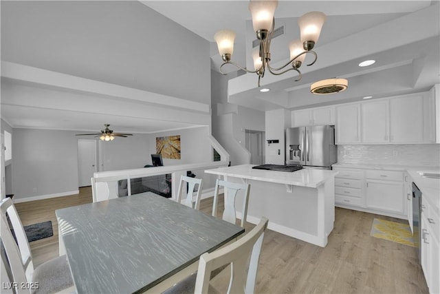 dining room featuring light wood-style floors, baseboards, and ceiling fan with notable chandelier