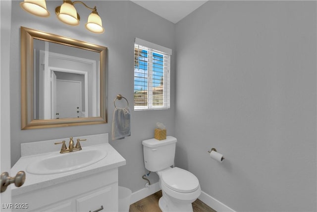bathroom featuring baseboards, wood finished floors, toilet, and vanity
