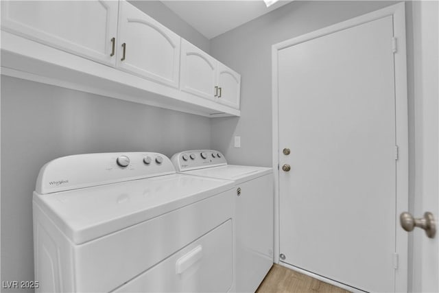 laundry area with cabinet space, separate washer and dryer, and light wood-type flooring