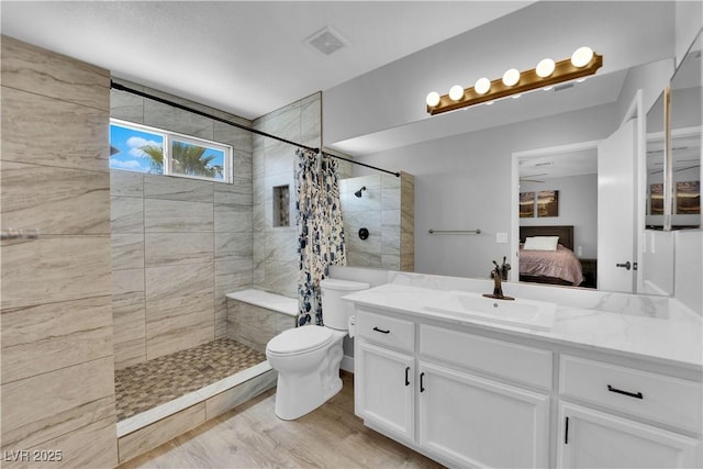 ensuite bathroom with visible vents, a tile shower, vanity, toilet, and ensuite bath