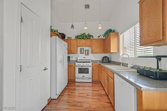 kitchen with visible vents, pendant lighting, a sink, light wood finished floors, and white appliances