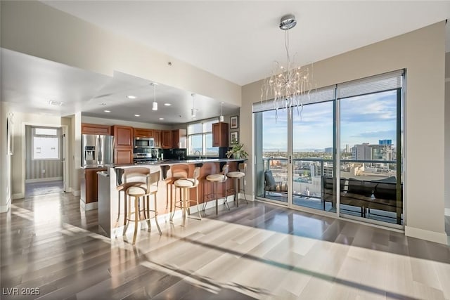 kitchen featuring appliances with stainless steel finishes, baseboards, brown cabinetry, and light wood-type flooring