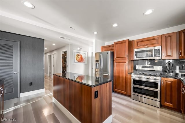 kitchen with a kitchen island, stainless steel appliances, light wood-style flooring, and visible vents
