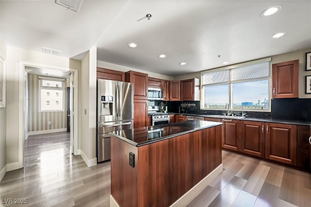 kitchen with a sink, appliances with stainless steel finishes, a center island, and visible vents